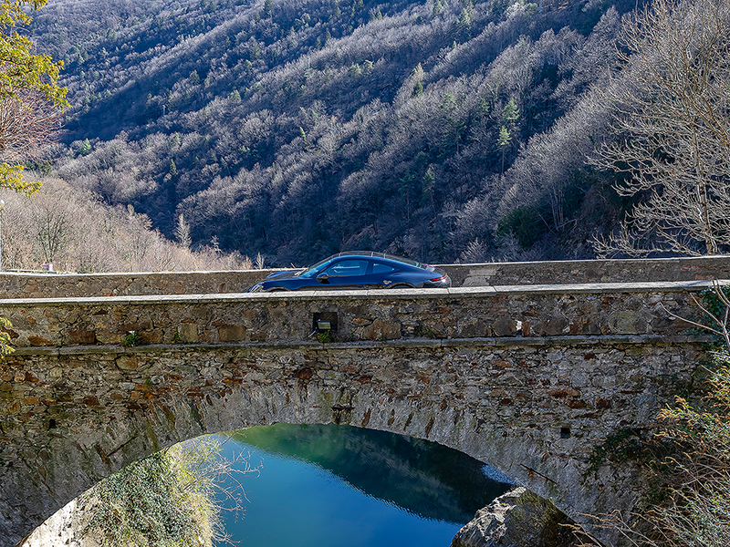 Porsche auf einer Steinbrücke über einem Tal